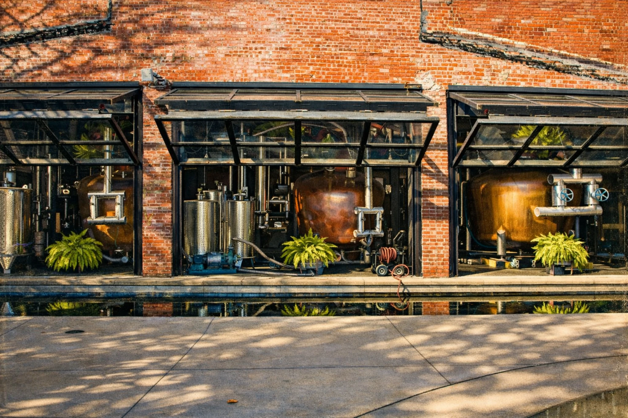 Exterior view of Copper & Kings Distillery with copper stills visible through open garage doors.