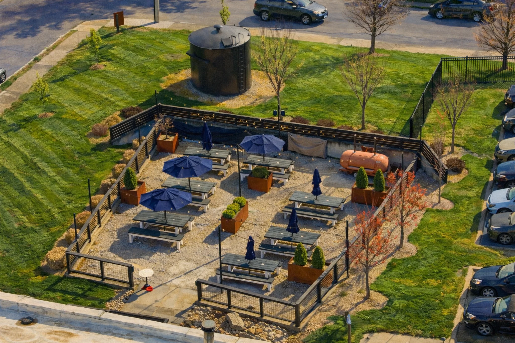 Aerial view of Hop Atomica’s fenced outdoor patio in Louisville, Kentucky with picnic tables and blue umbrellas.