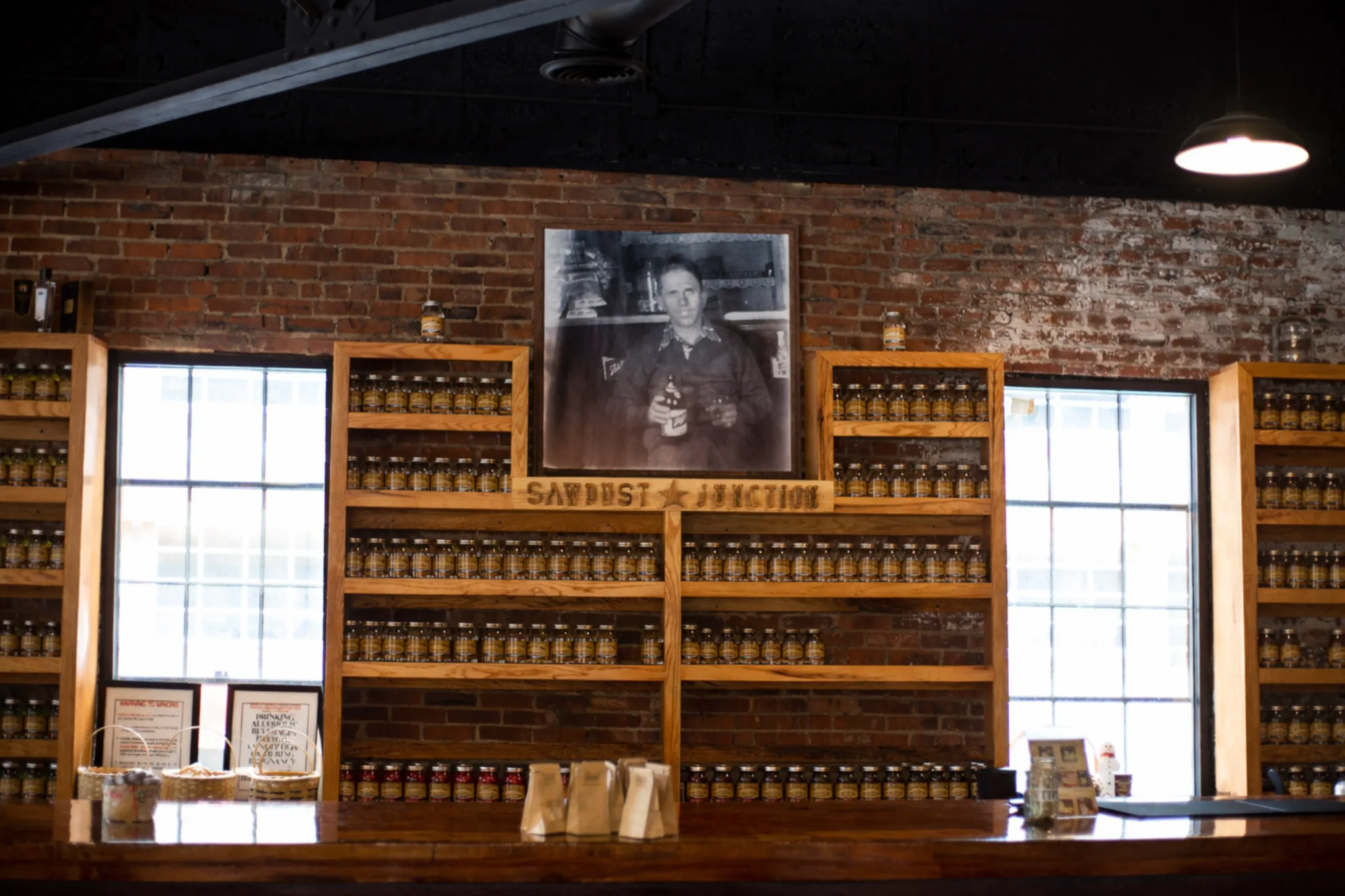 Sawdust Junction shelves inside Kentucky Mist Distillery in Whitesburg, Kentucky with rows of jars and a vintage portrait above.