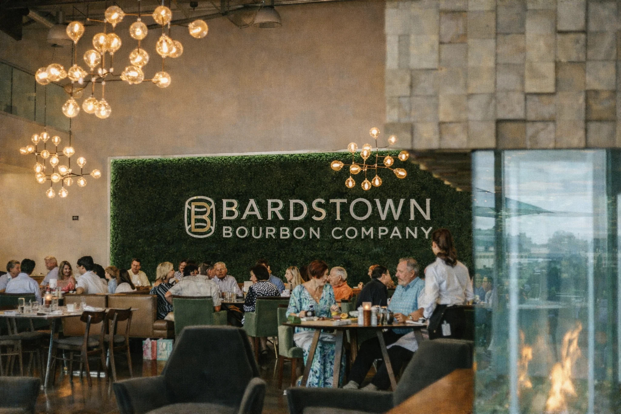 Interior dining area at Kitchen & Bar inside of Bardstown Bourbon Company restaurant with guests seated beneath modern lighting.