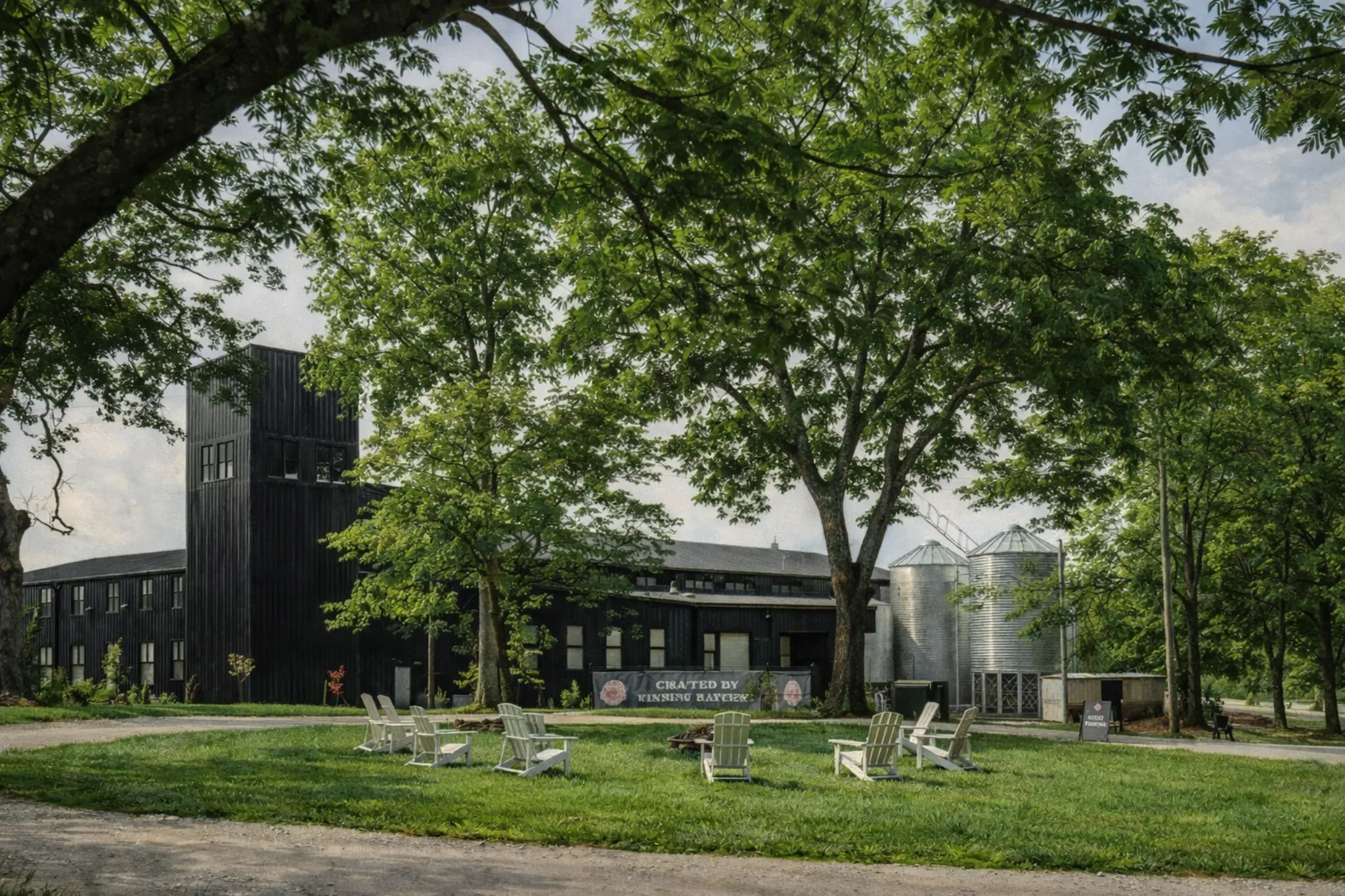 Exterior view of Bluegrass Distillers at Elkwood Farms featuring modern distillery buildings surrounded by trees and outdoor seating on the lawn.
