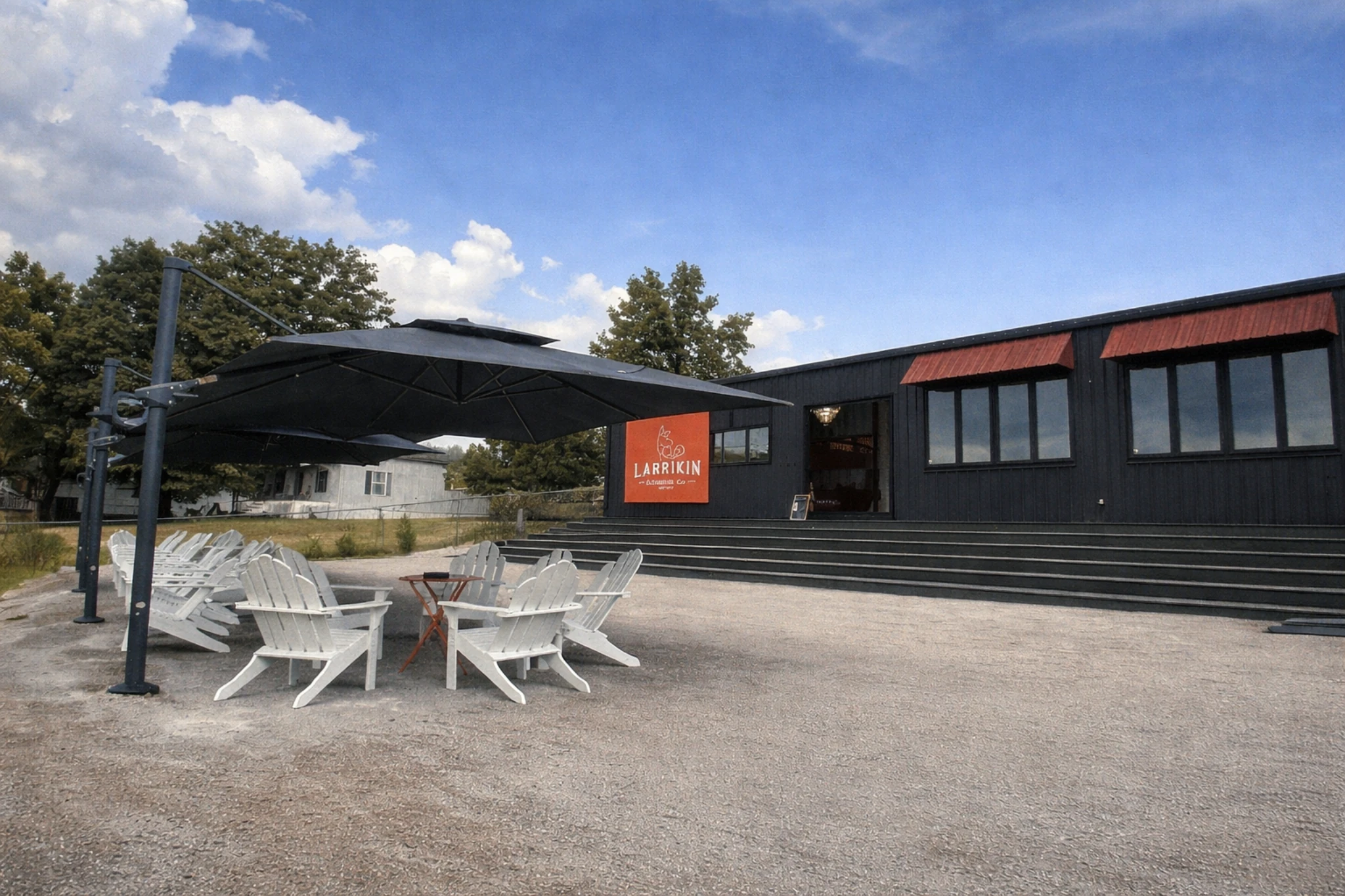 Outdoor seating area at Larrikin Bourbon Company with chairs, umbrellas, and black-clad building.