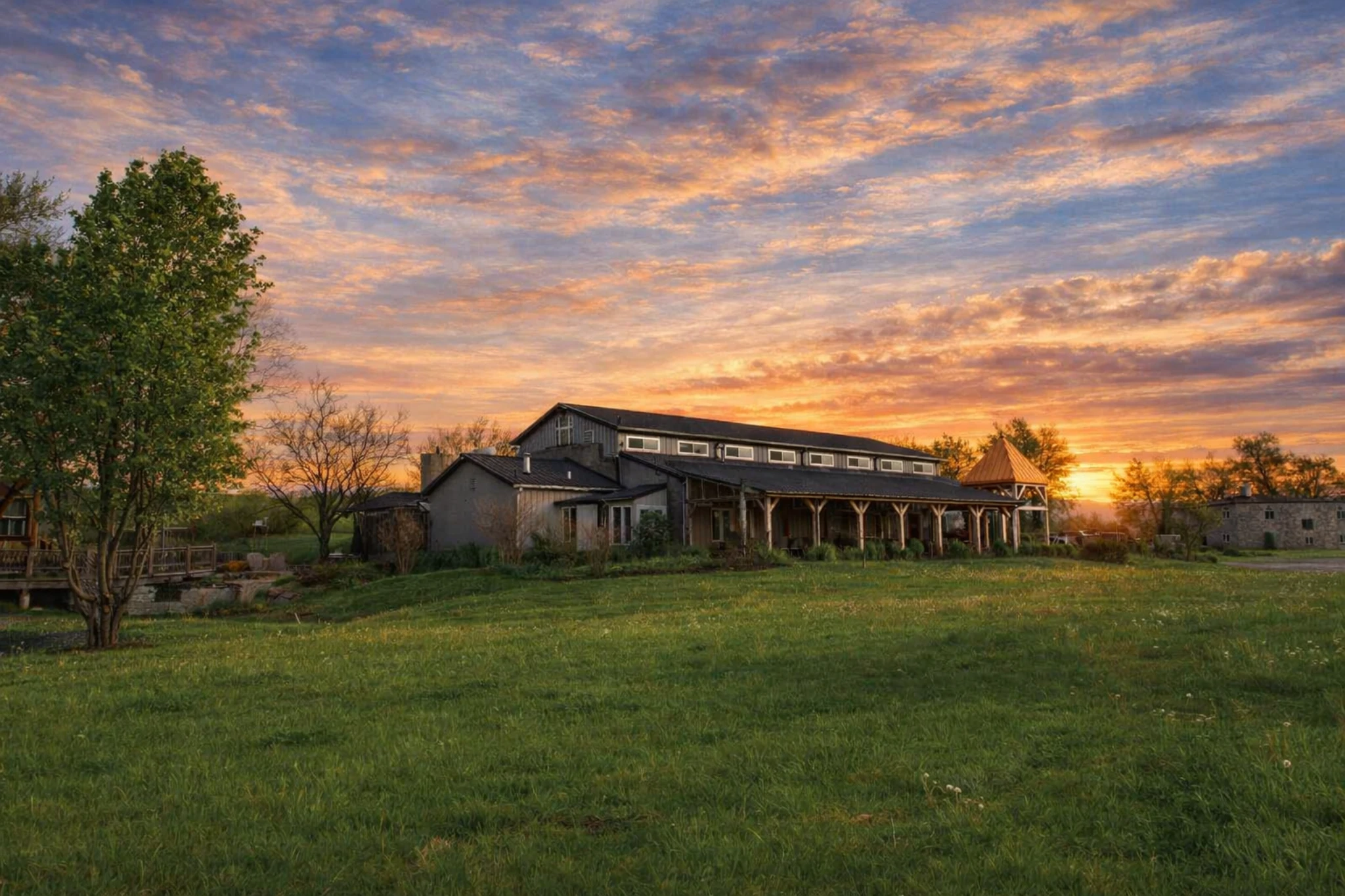 Main Limestone Branch Distillery building set on rolling green grounds during a colorful sunset.