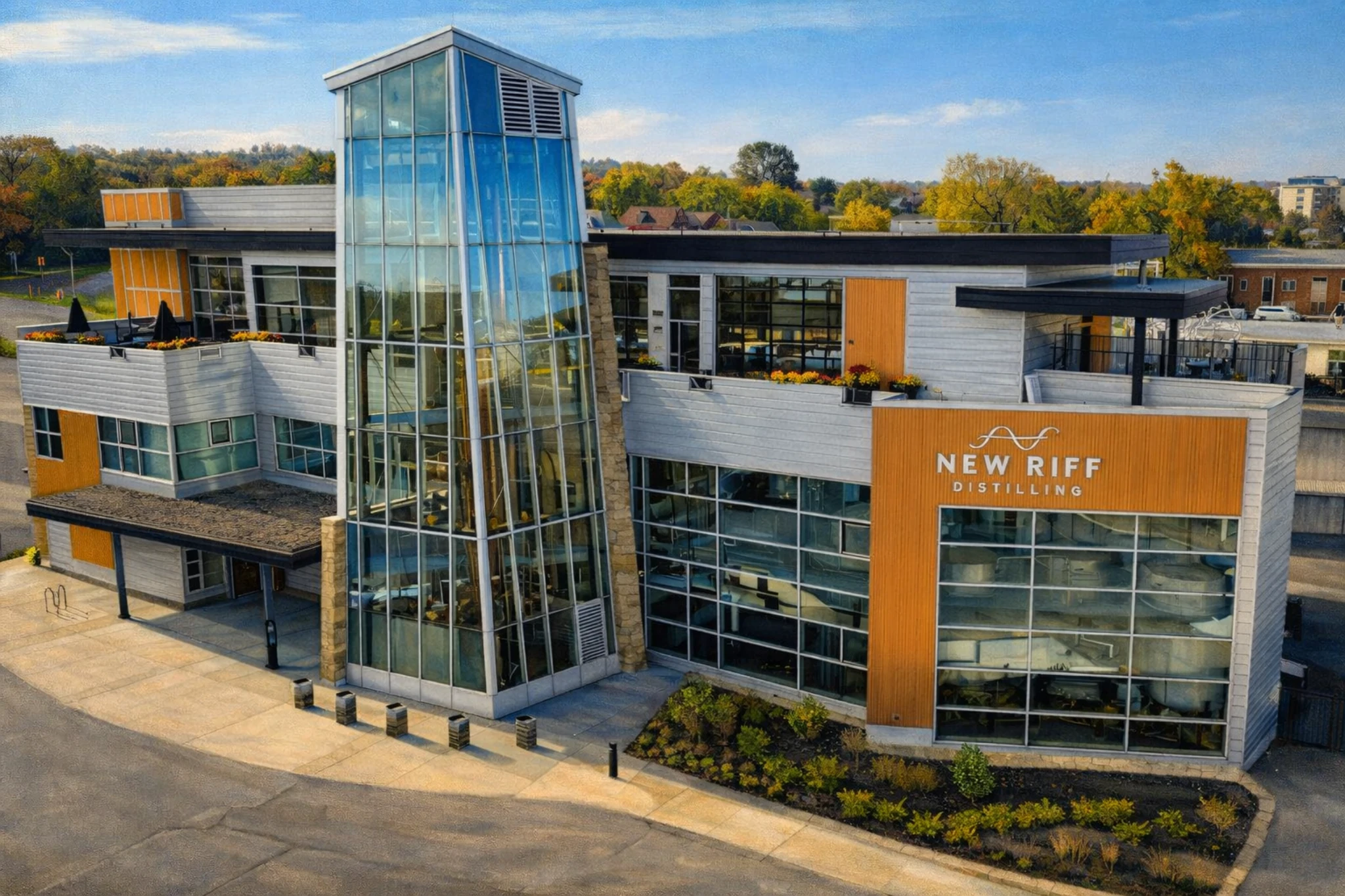 Aerial view of the New Riff Distilling facility showing the glass tower, rooftop patio areas, and New Riff Distilling signage.