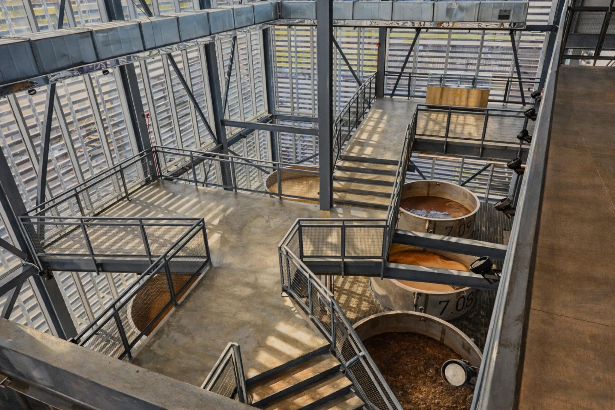 Multi-level fermentation floor at Rabbit Hole Distillery with large open-top fermentation tanks and metal walkways.