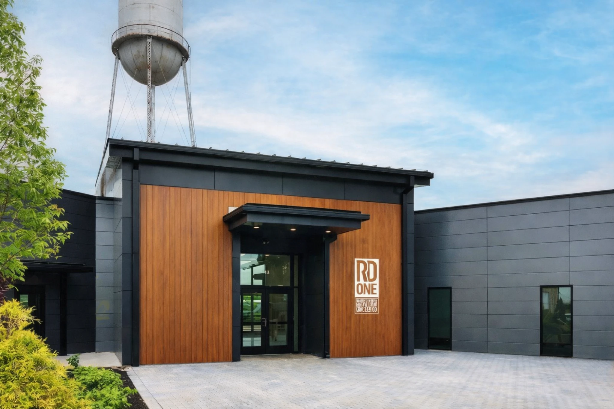 Front entrance of RD1 Spirits Distillery with wood-accented facade and historic water tower visible above the building.