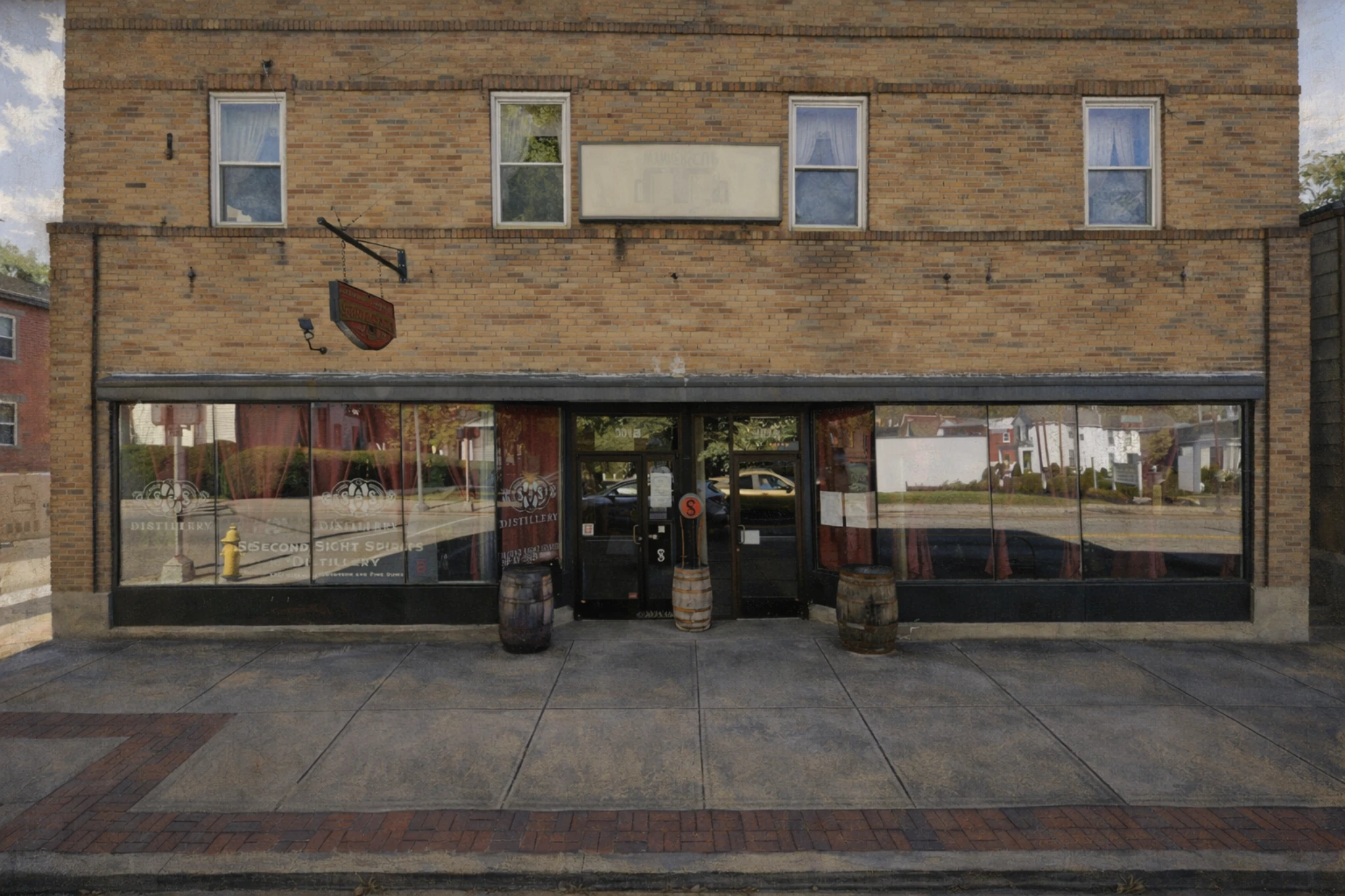 Brick storefront exterior of Second Sight Spirits Distillery with large display windows, barrels outside the entrance, and downtown sidewalk frontage.