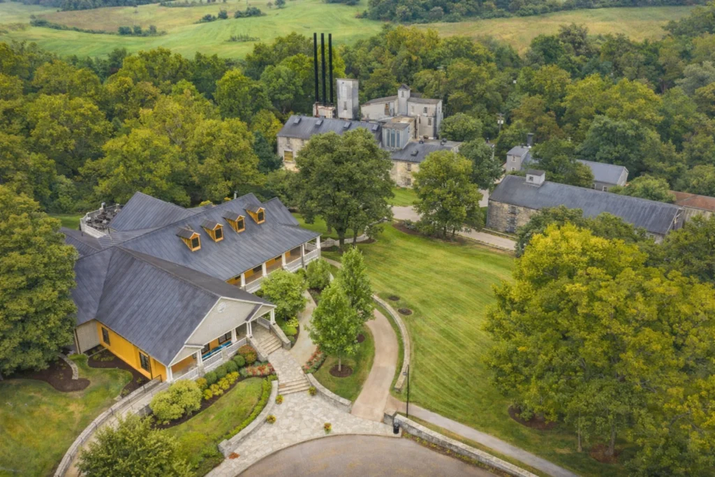 Aerial view of Woodford Reserve Distillery buildings and rolling green hills in rural Kentucky.