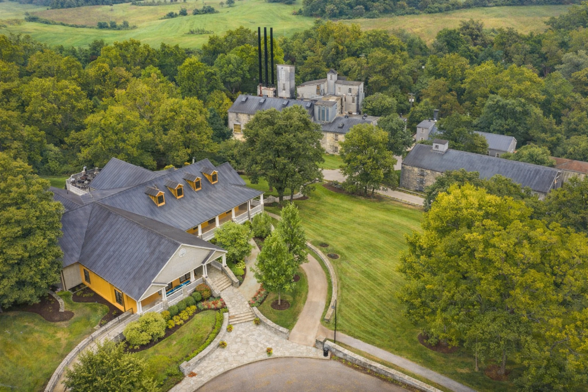 Aerial view of Woodford Reserve Distillery buildings and rolling green hills in rural Kentucky.