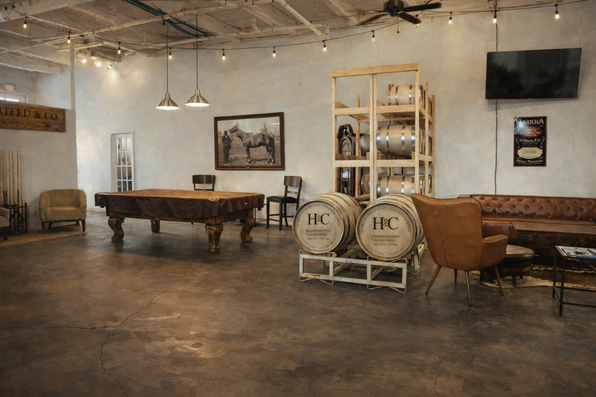 Tasting room lounge area at Hartfield & Co. Distillery with pool table, leather seating, and barrel display.