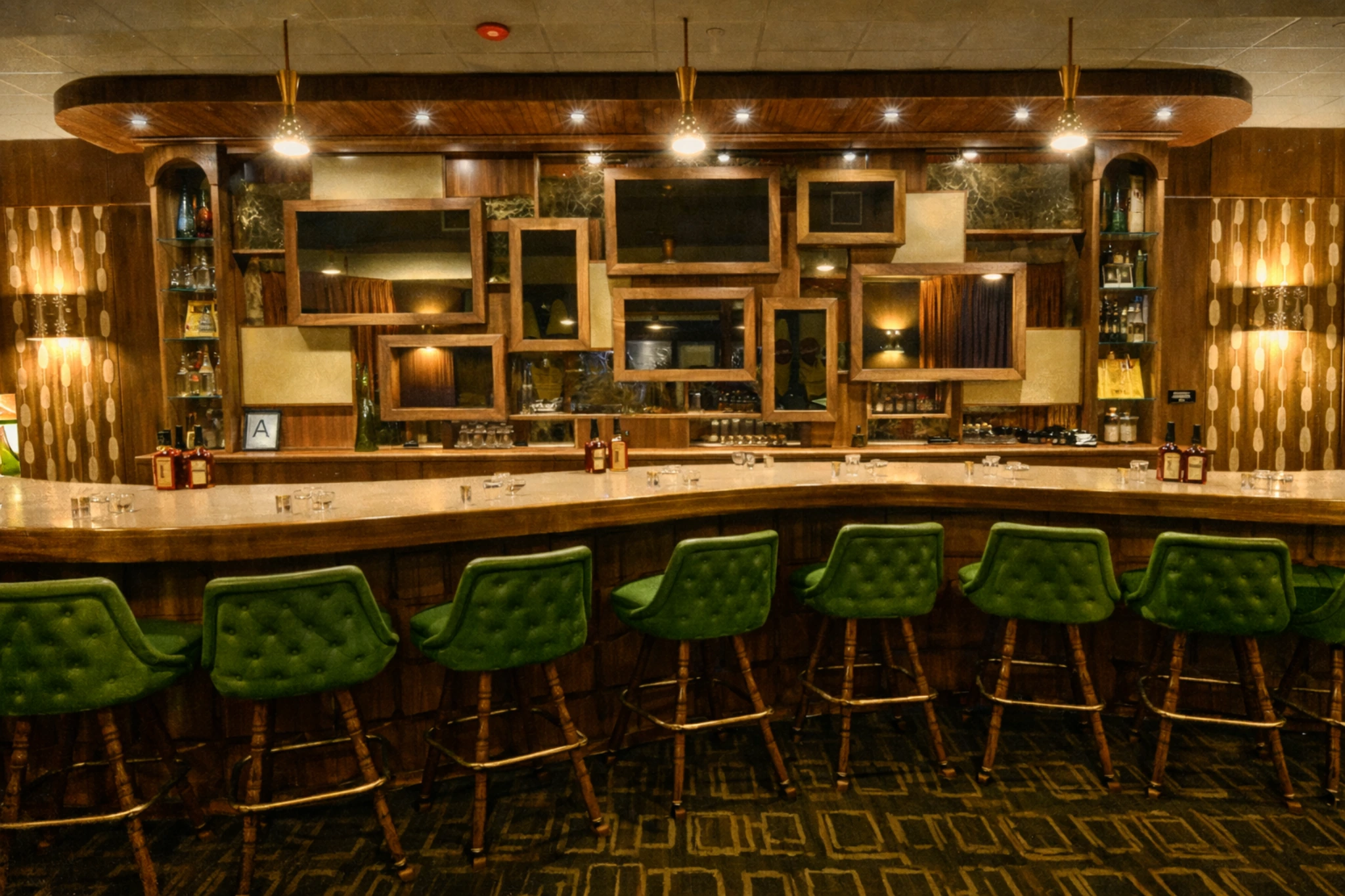 Modern tasting bar at the Evan Williams Bourbon Experience with green barstools and a wood-framed mirrored backdrop.